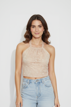 Woman wearing a beige lace halter top and light blue denim shorts on a white background