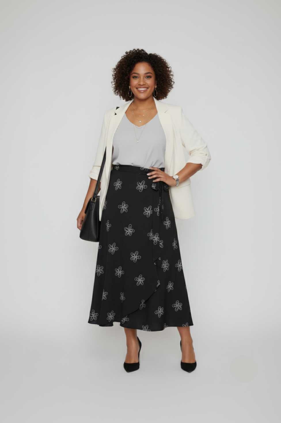 Woman wearing a black patterned skirt, white top, and cream cardigan on a white background