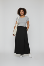 Woman wearing a gray t-shirt and black wrap skirt with a white background