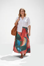 Woman wearing a white shirt and colorful skirt with a brown bag on a white background