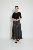 Woman wearing a black top and floral skirt on a white background