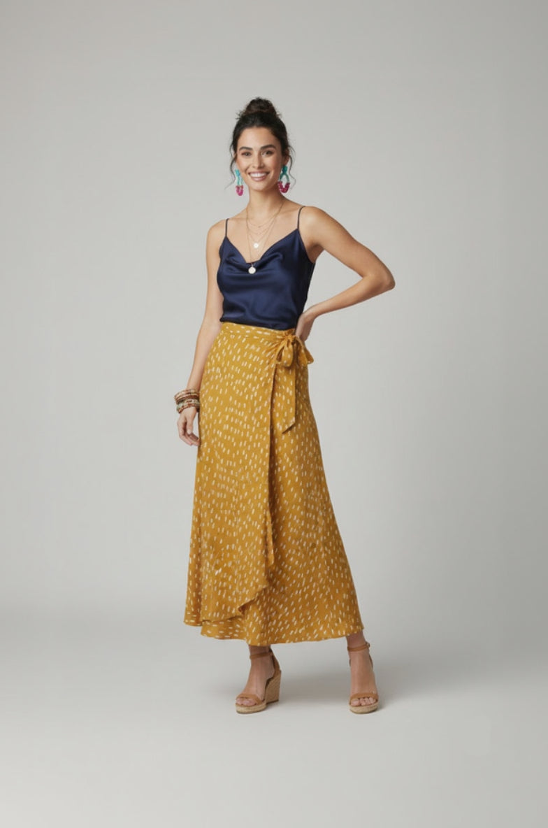 Woman wearing a navy top and yellow patterned skirt on a gray background