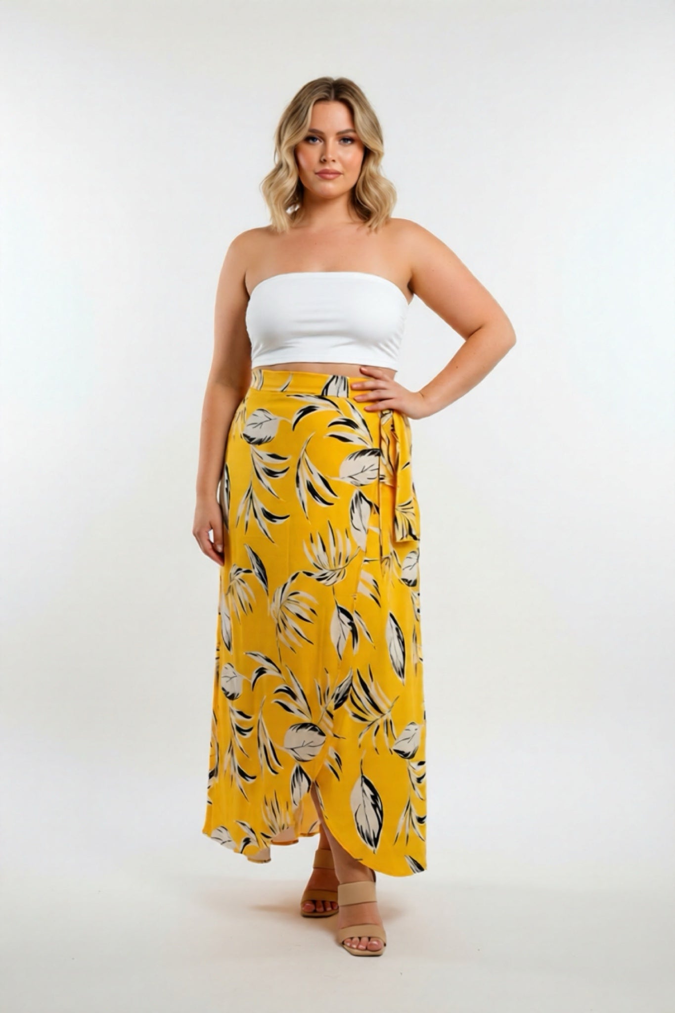 Woman wearing a white top and yellow floral skirt on a white background