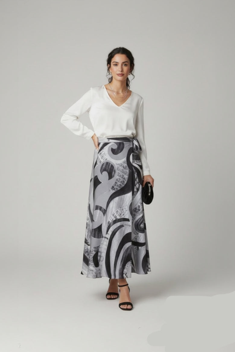 Woman wearing a white top and patterned skirt on a gray background