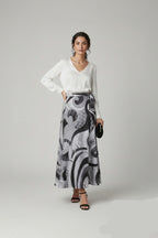 Woman wearing a white top and patterned skirt on a gray background