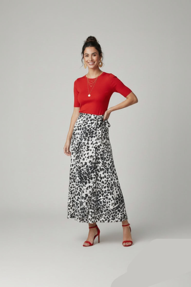 Woman wearing a red top and black and white patterned skirt on a gray background