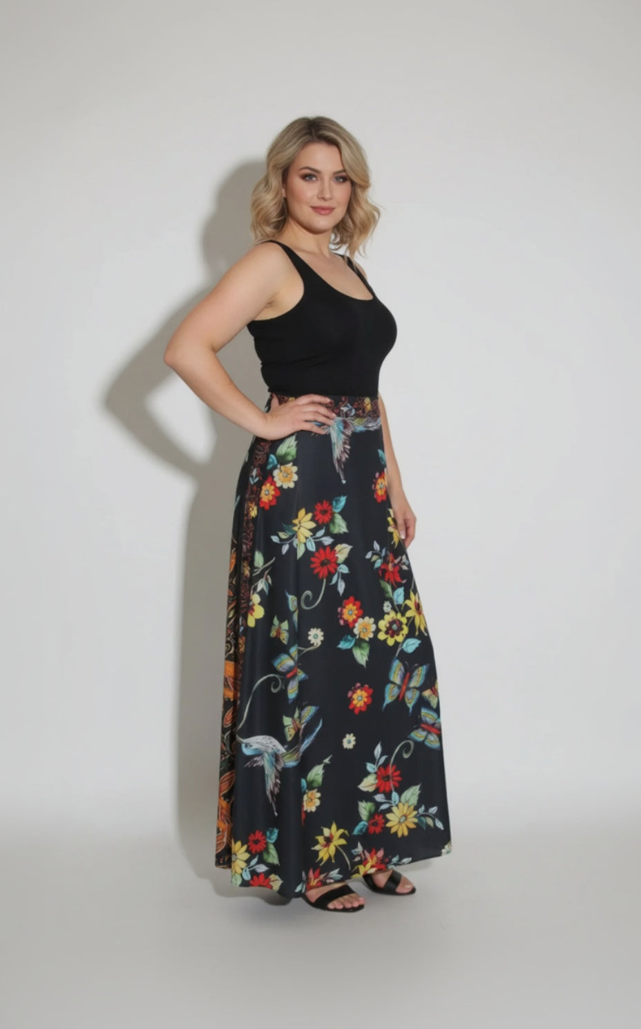 Woman wearing a black top and floral skirt on a white background