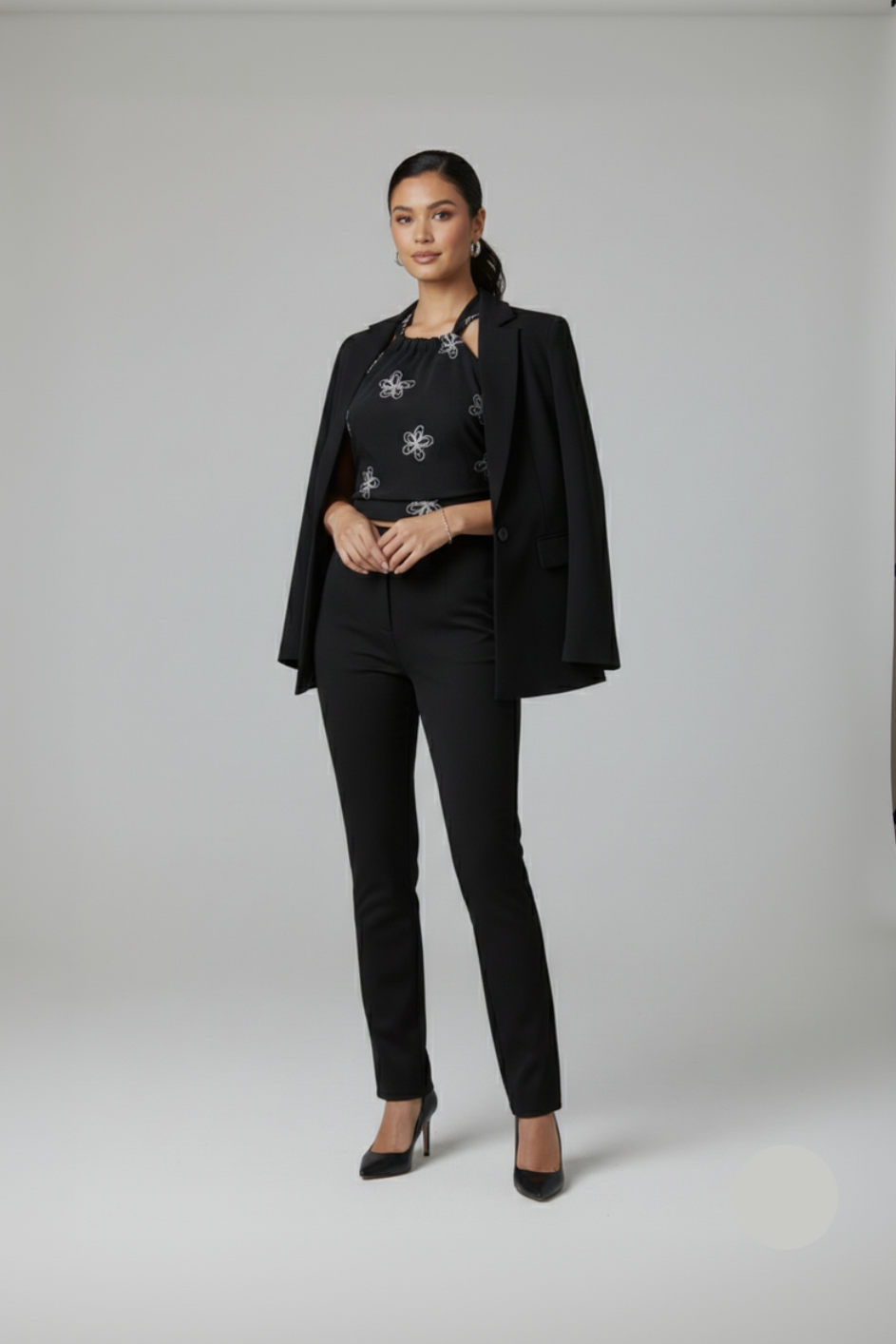 Woman wearing a black suit with a patterned top on a gray background
