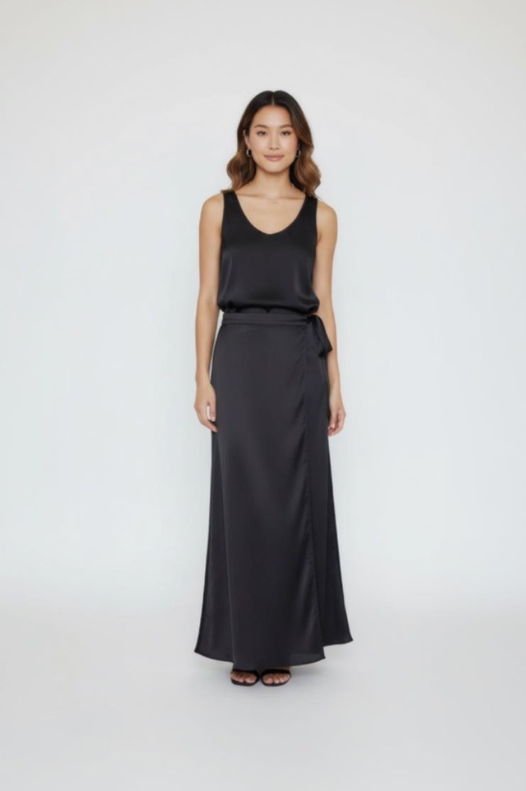 Woman wearing a black sleeveless top and long black satin skirt on a white background