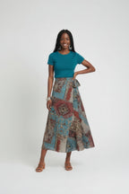 Woman wearing a teal top and patterned skirt on a white background