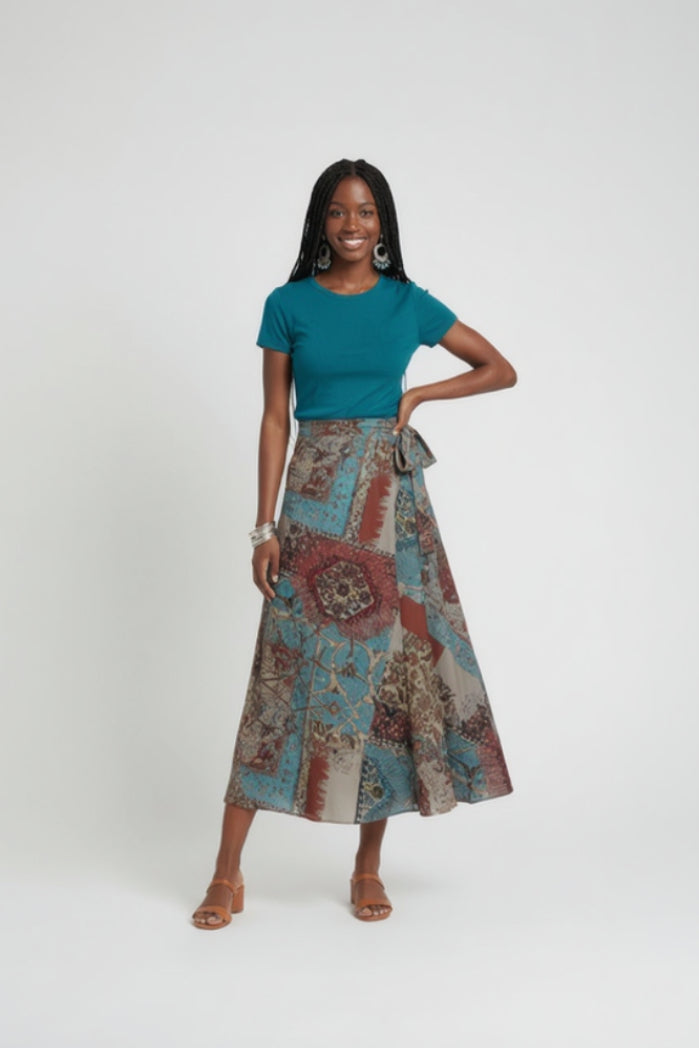 Woman wearing a teal top and patterned skirt on a white background