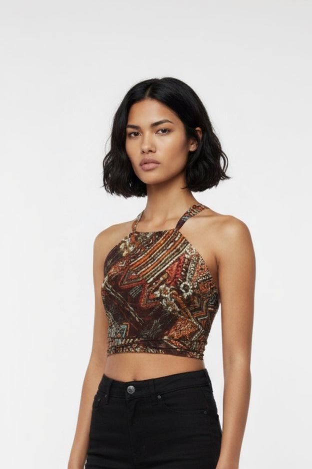 Woman wearing a brown patterned top and black jeans on a white background