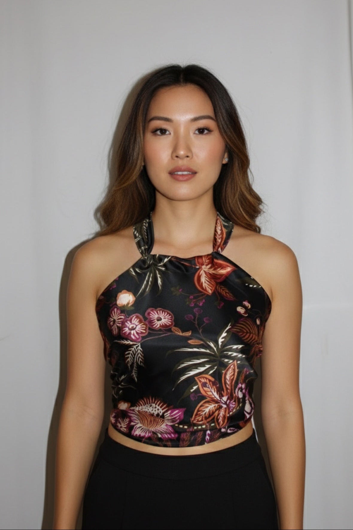 Woman wearing a black floral halter top against a plain background
