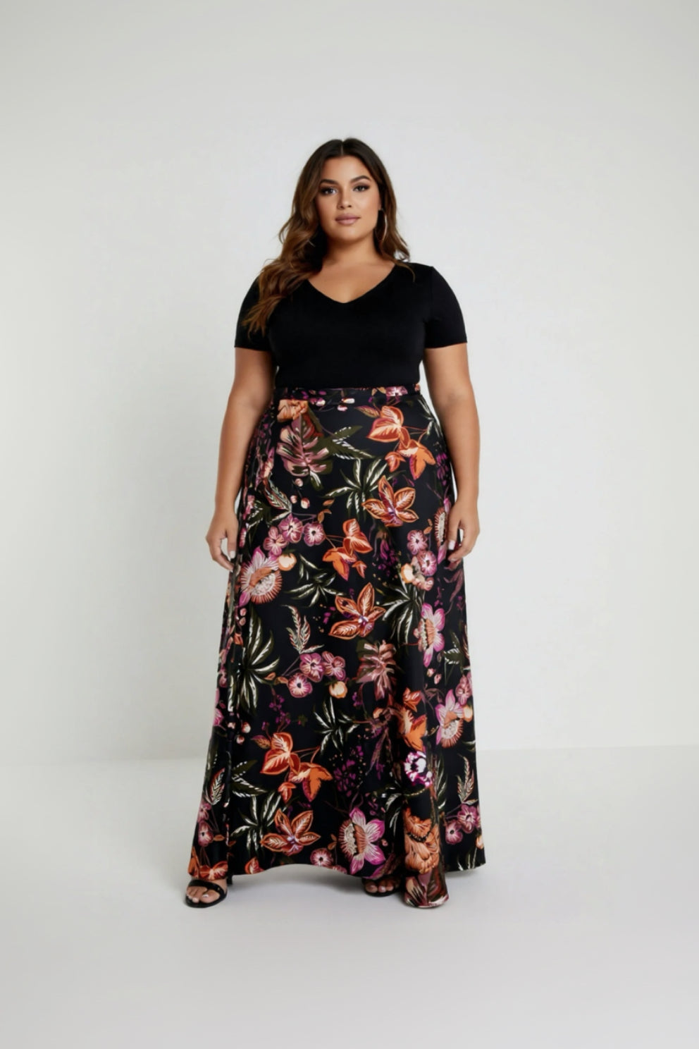 Woman wearing a black top and a long floral skirt on a white background
