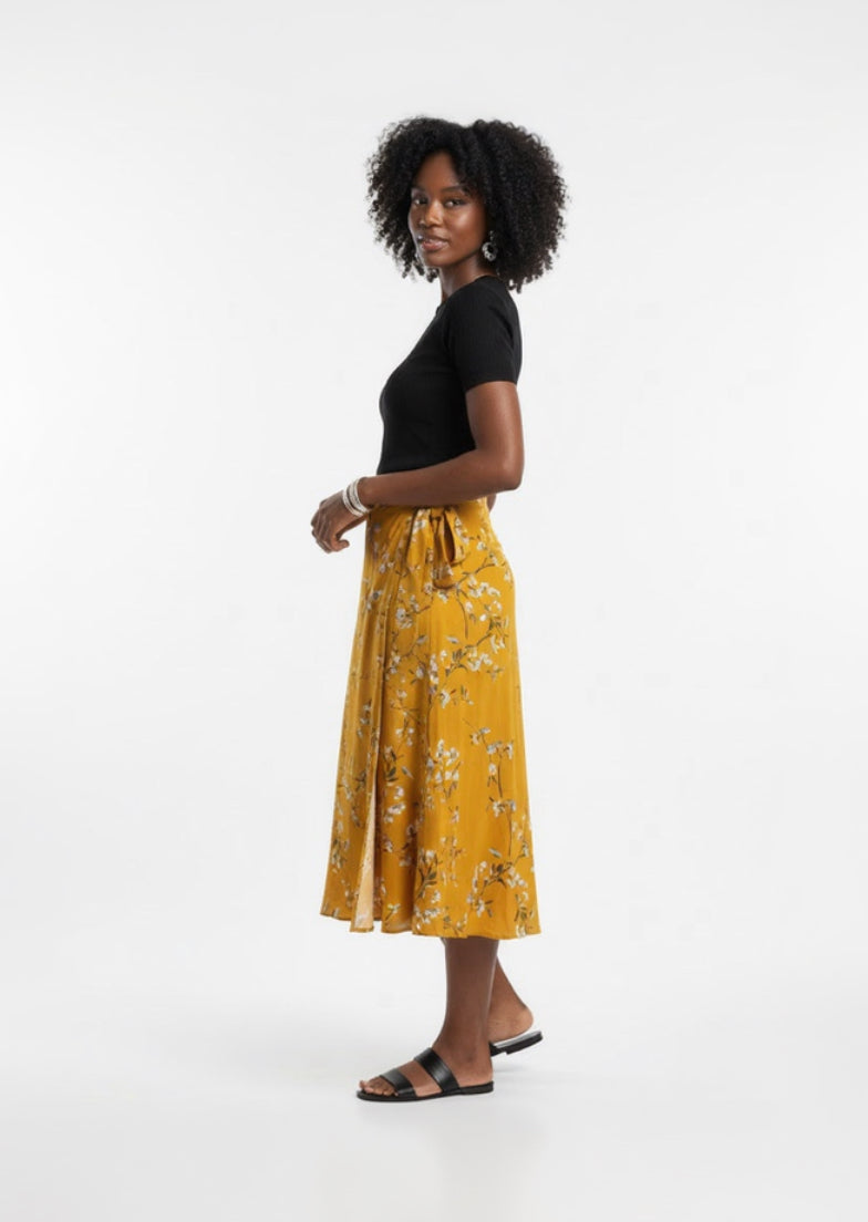 Woman wearing a yellow floral skirt and black top on a white background