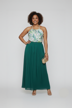 Woman wearing a floral top and green skirt with a white background