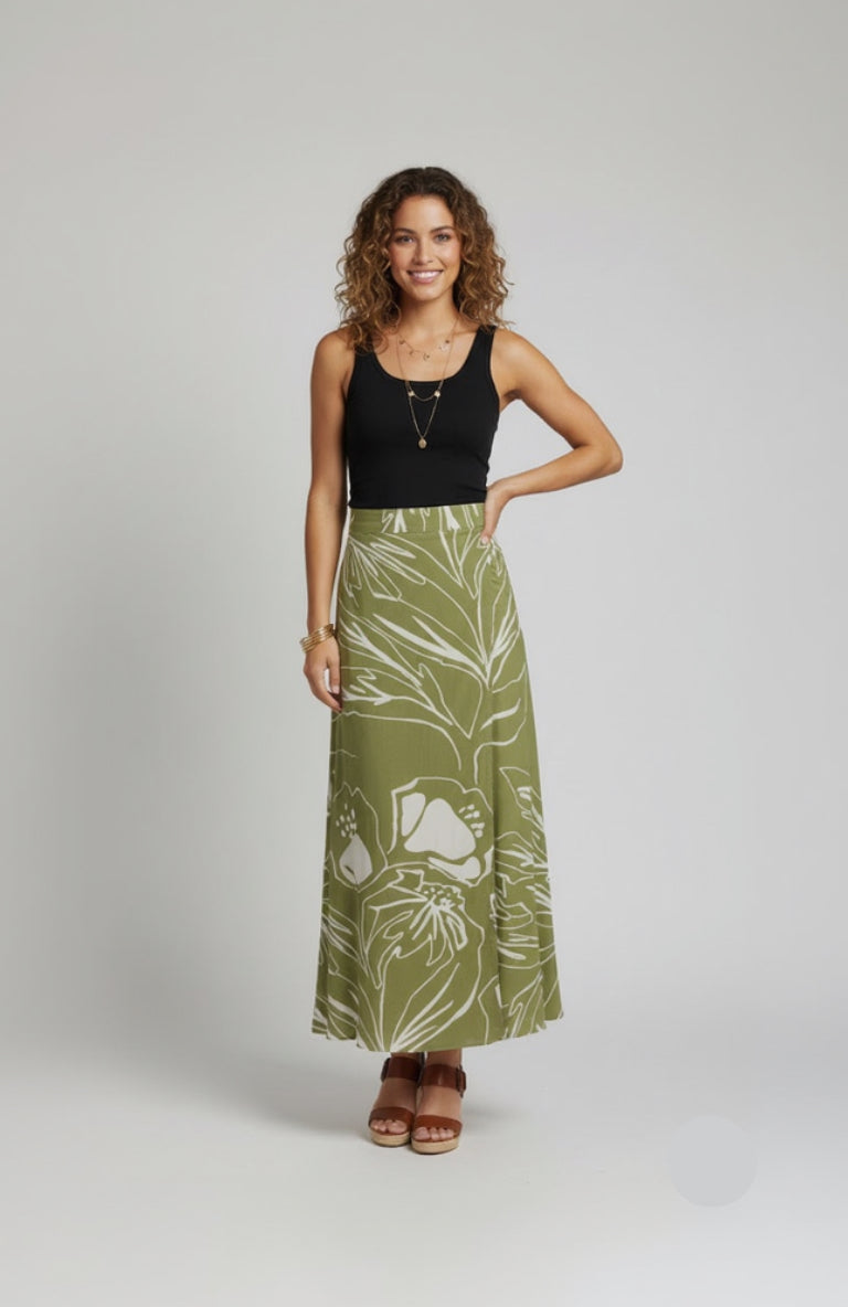 Woman wearing a black tank top and green floral skirt on a gray background