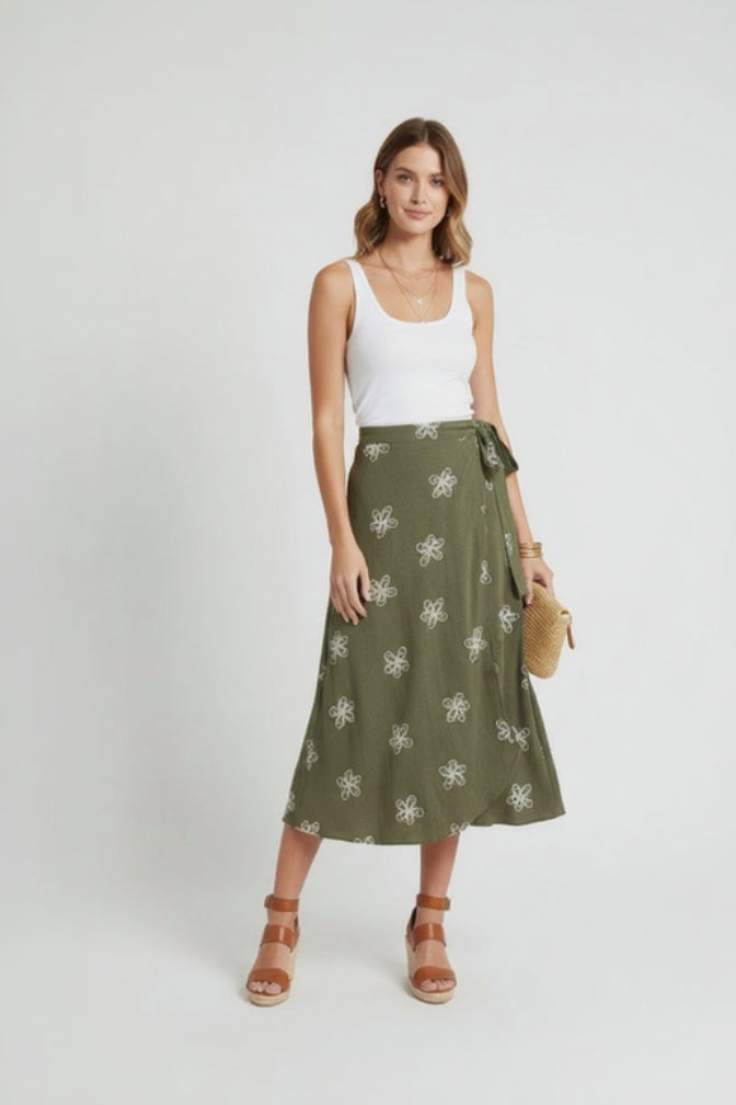 Woman wearing a white tank top and green patterned skirt on a white background