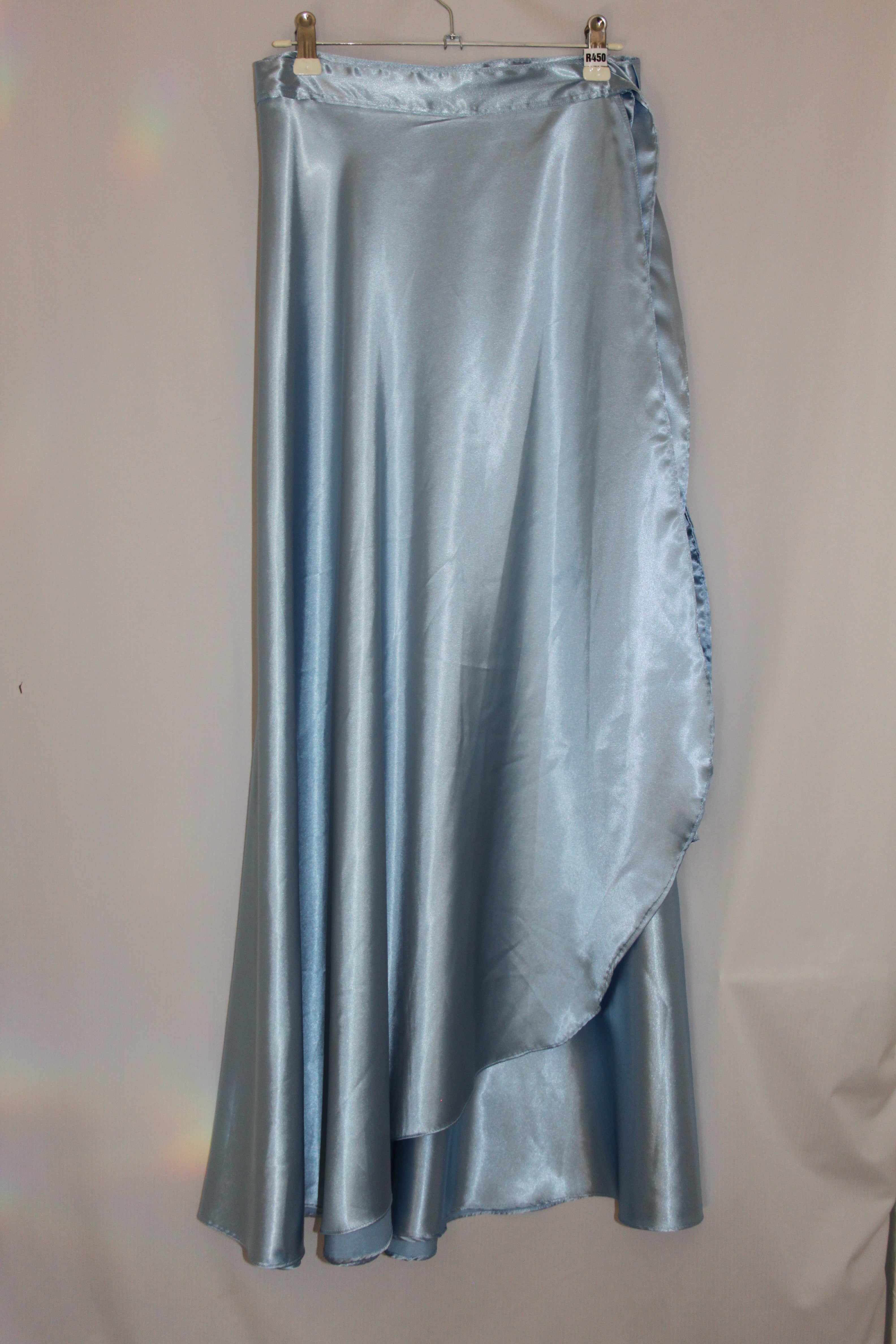blue satin skirt hanging on white background