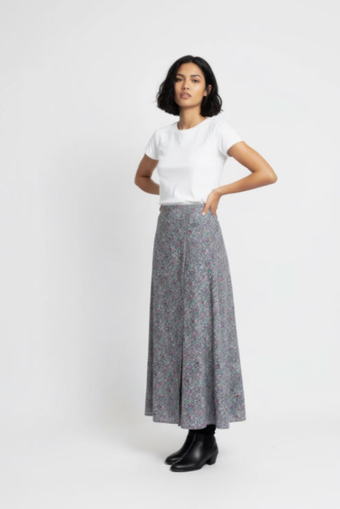 Woman wearing a white t-shirt and gray floral skirt on a white background