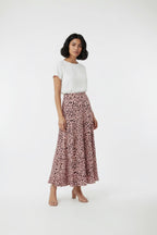 Woman wearing a white top and pink leopard print skirt on a white background