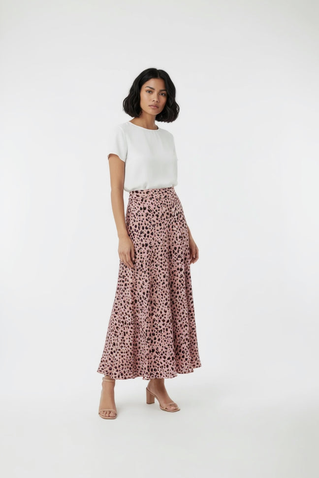 Woman wearing a white top and pink leopard print skirt on a white background