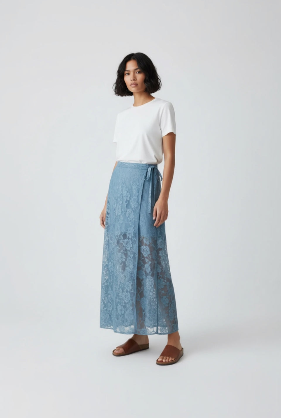 Woman wearing a white top and blue lace skirt on a white background